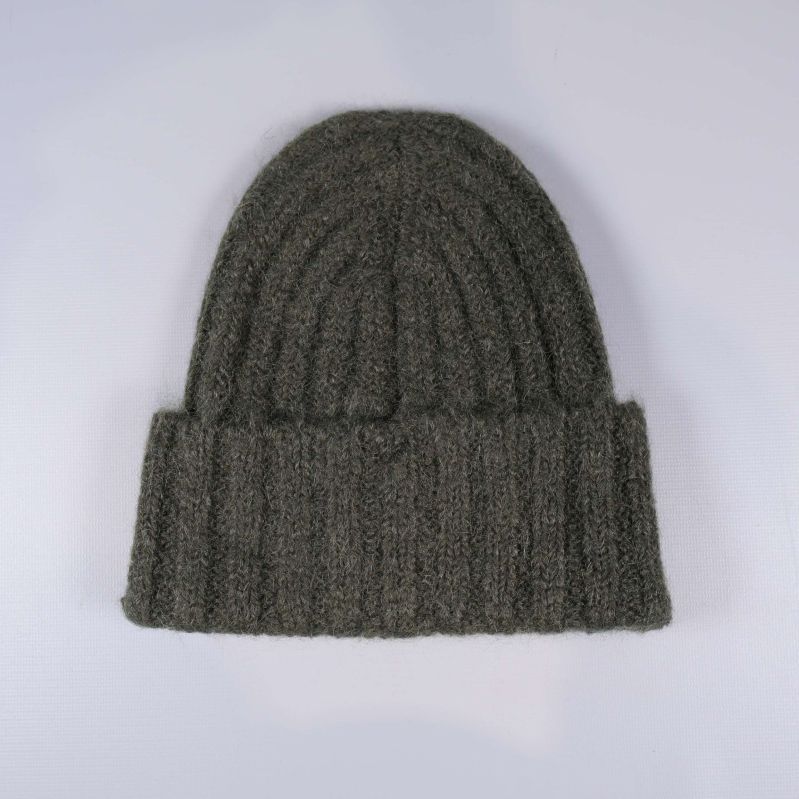 Grön mössa liggande med synlig stickad struktur