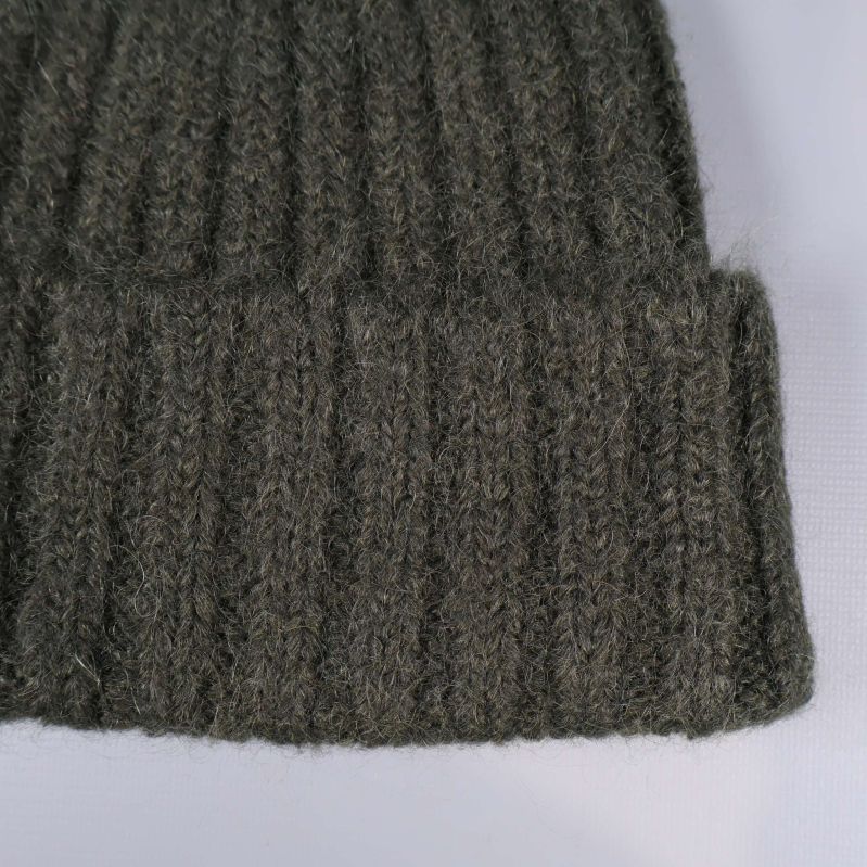 Närbild på ribbstickad grön mössa med uppvik