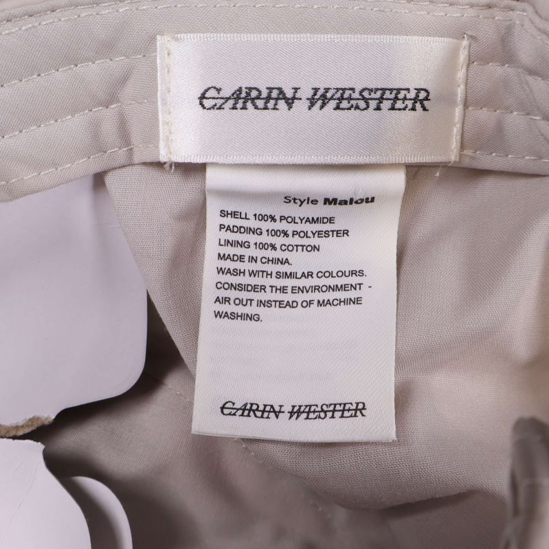 Närbild på Carin Wester-etikett och materialinformation i kepsen