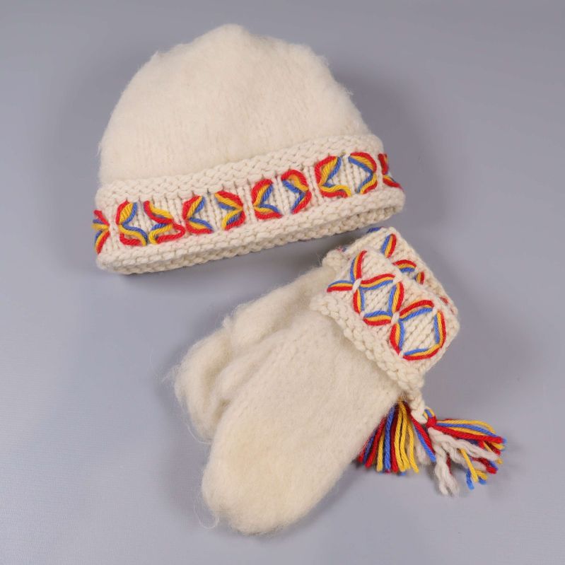 Ullmössa och vantar liggande på grå bakgrund med mönsterdetaljer