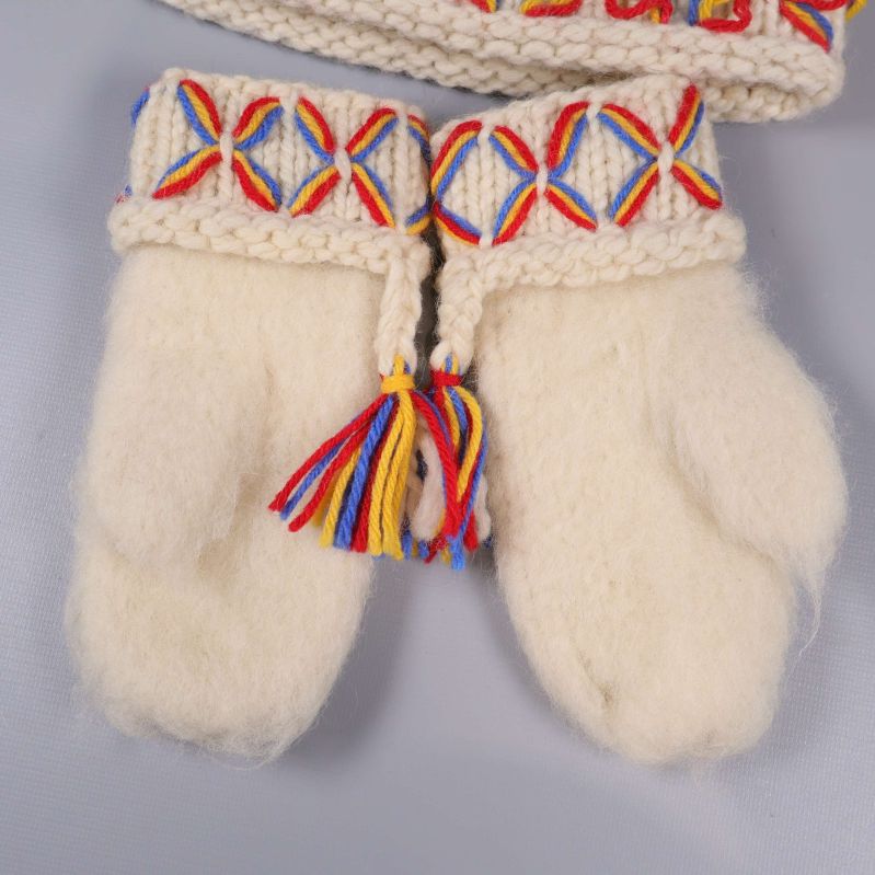 Närbild på ullvantar med färgglada broderier och tofsar