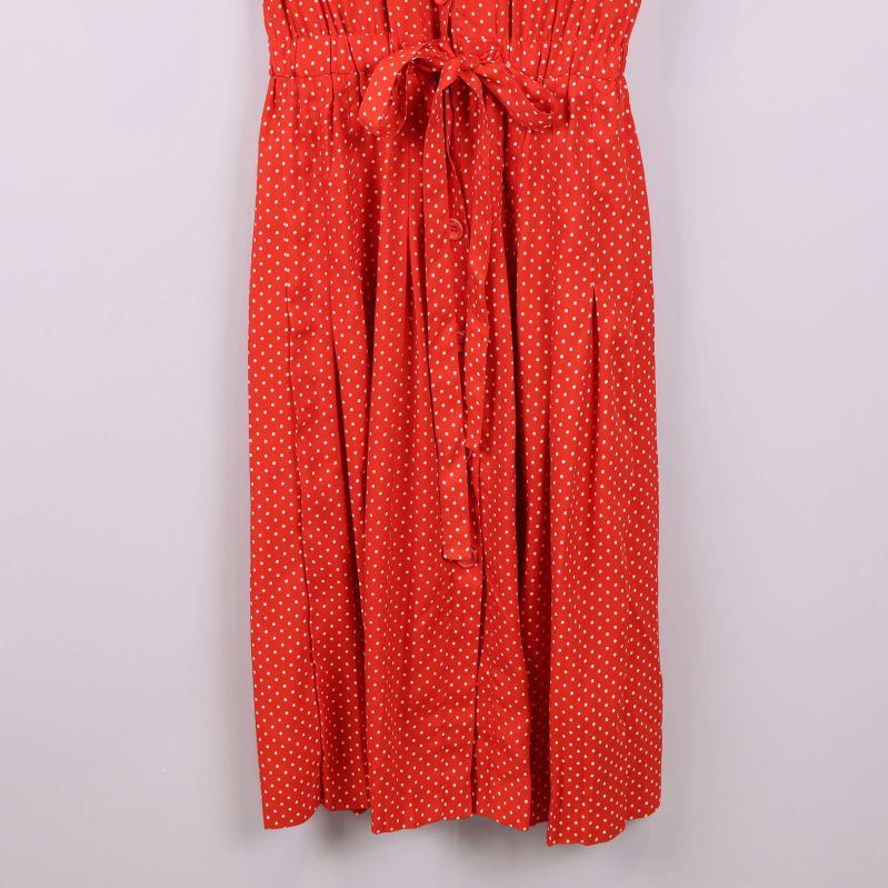 Nedre delen av rödprickig klänning med knytband och veck