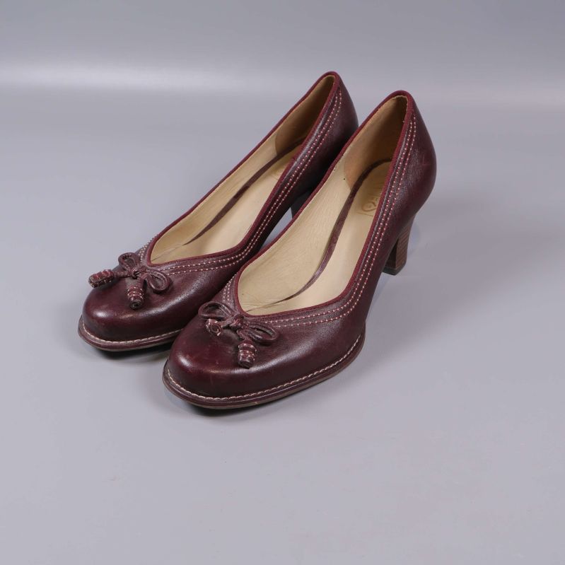 Vinröda pumps med rosetter i trekvartsprofil