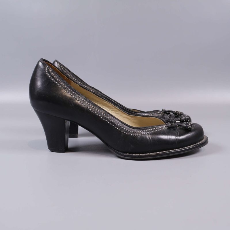 Profil av svarta pumps med klack och rosett framtill