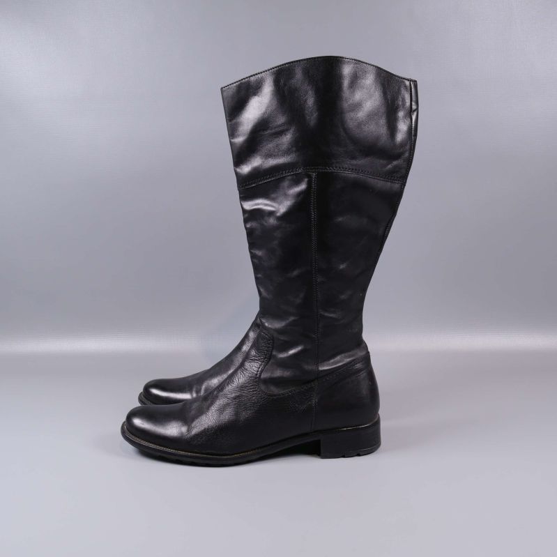 Höga svarta stövlar i profil mot grå bakgrund