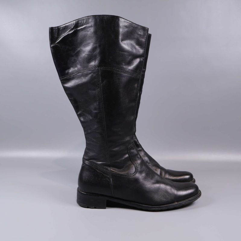 Sidovy på höga svarta stövlar mot grå bakgrund