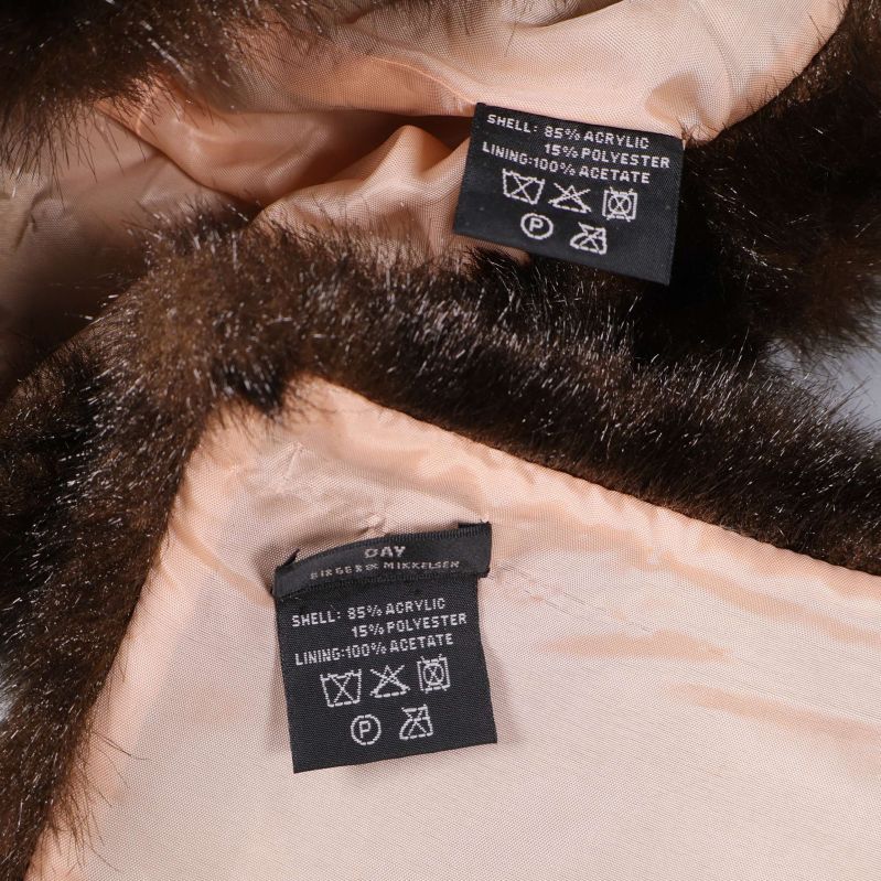 Två tvättetiketter som visar material i mössa och halsduk