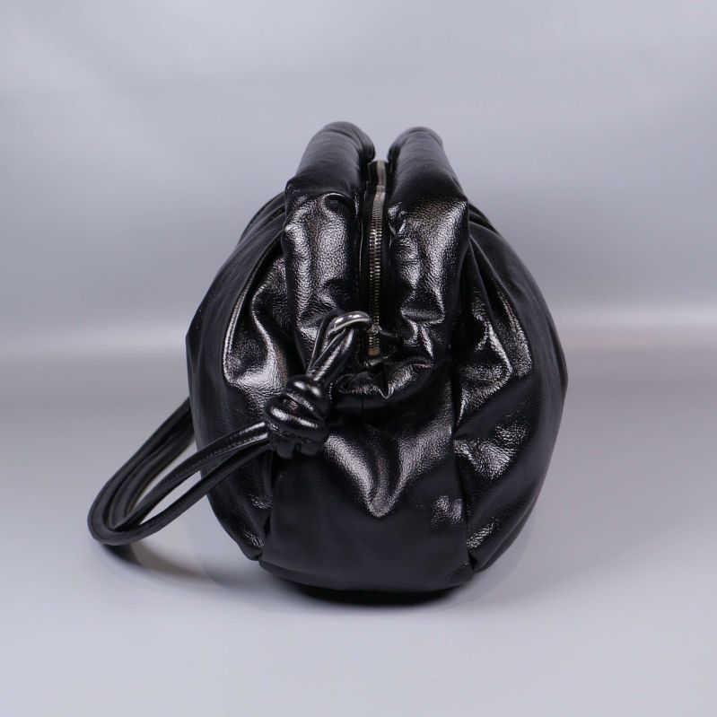 Sidan av puffig svart väska med knut på remfästet