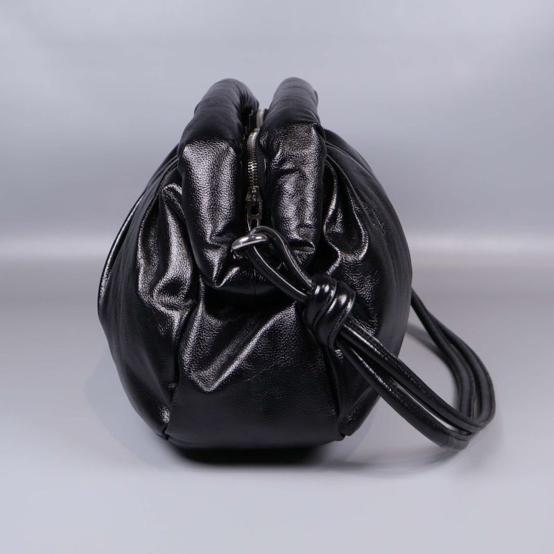 Sida av svart väska med synlig dragkedja och knut på remmen