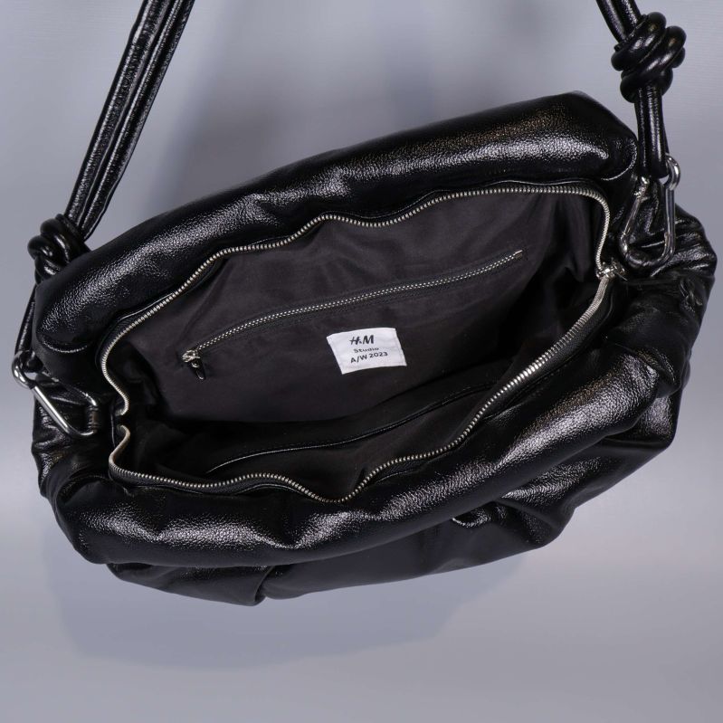 Insidan av svart väska med dragkedjefack och synlig H&M-etikett