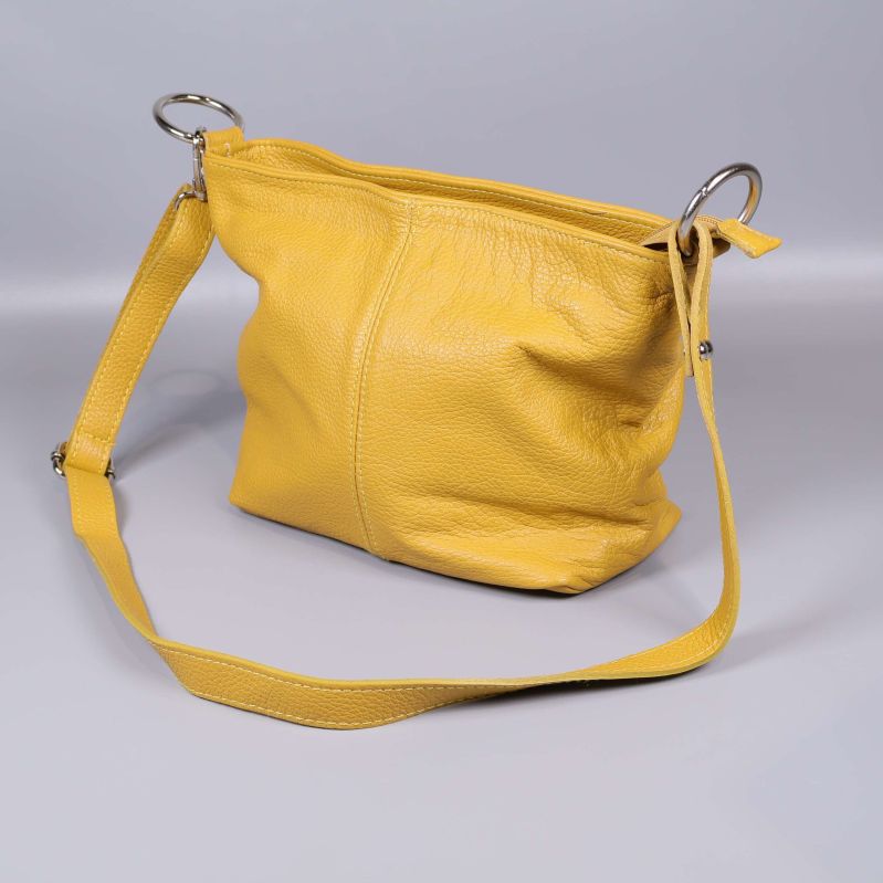 Gul läderväska med axelrem och metallringar