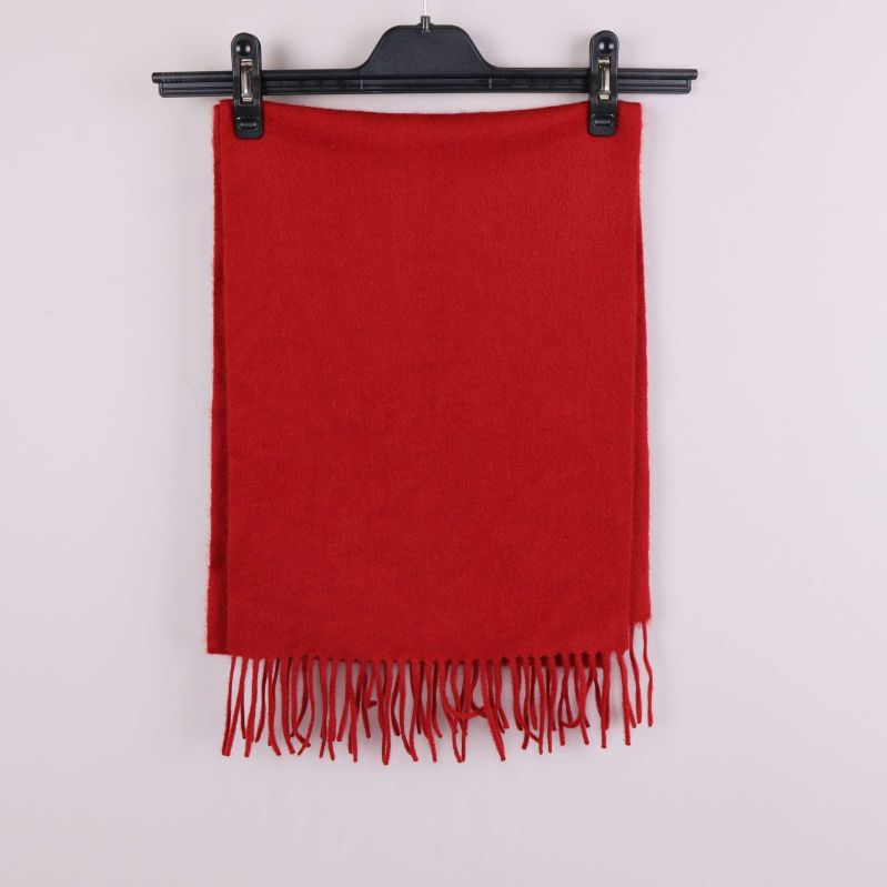 Röd halsduk med fransar hänger utsträckt på galge