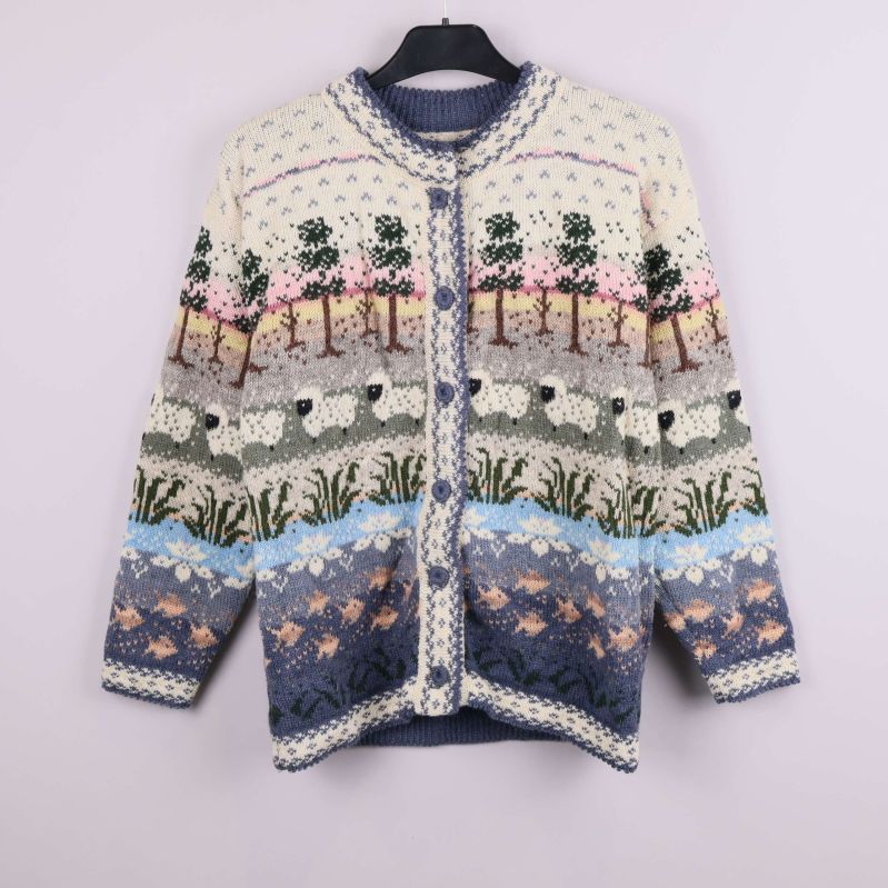 Flerfärgad stickad kofta med landskap och djurmotiv hängande på galge