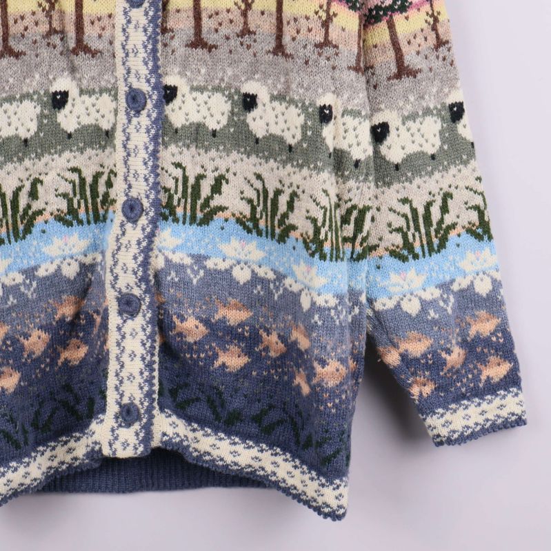 Närbild av nedre framstycke på mönsterstickad kofta med fiskar och får