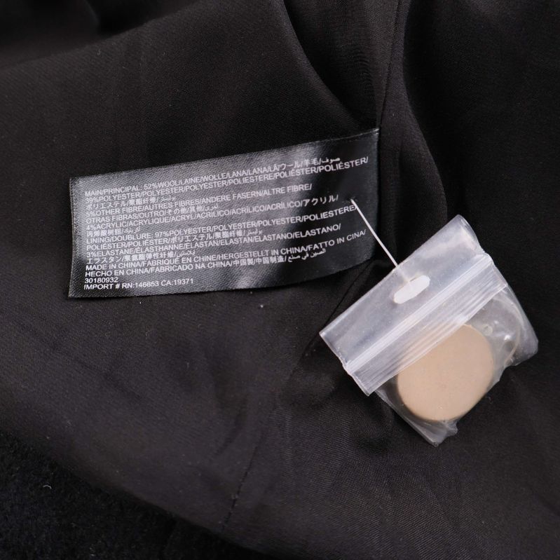 Materiallapp och extra knapp i plastpåse på svart tyg