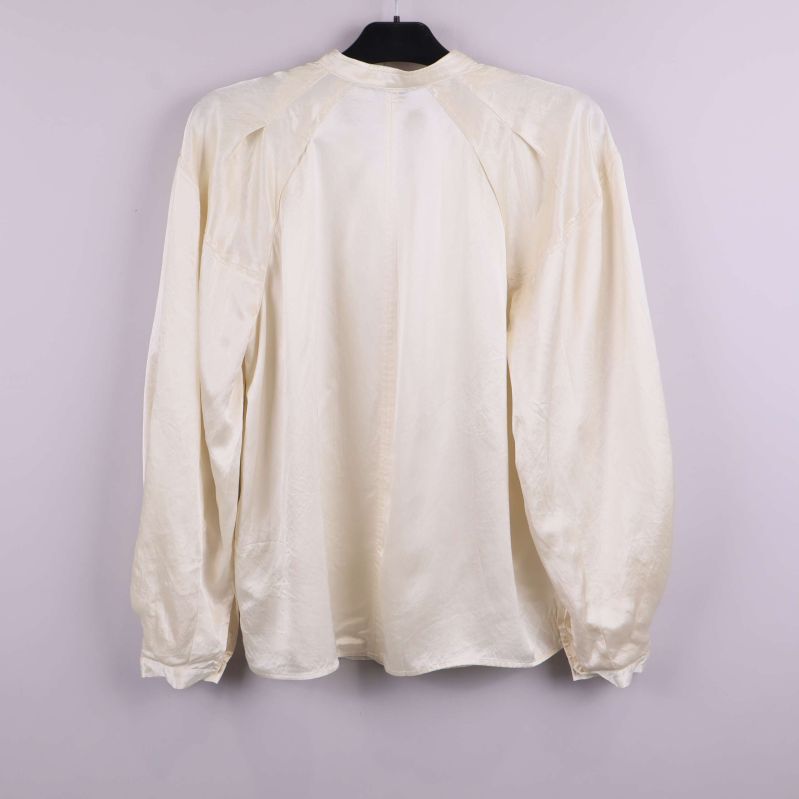 Ljus blus med lång ärm bakifrån på galge