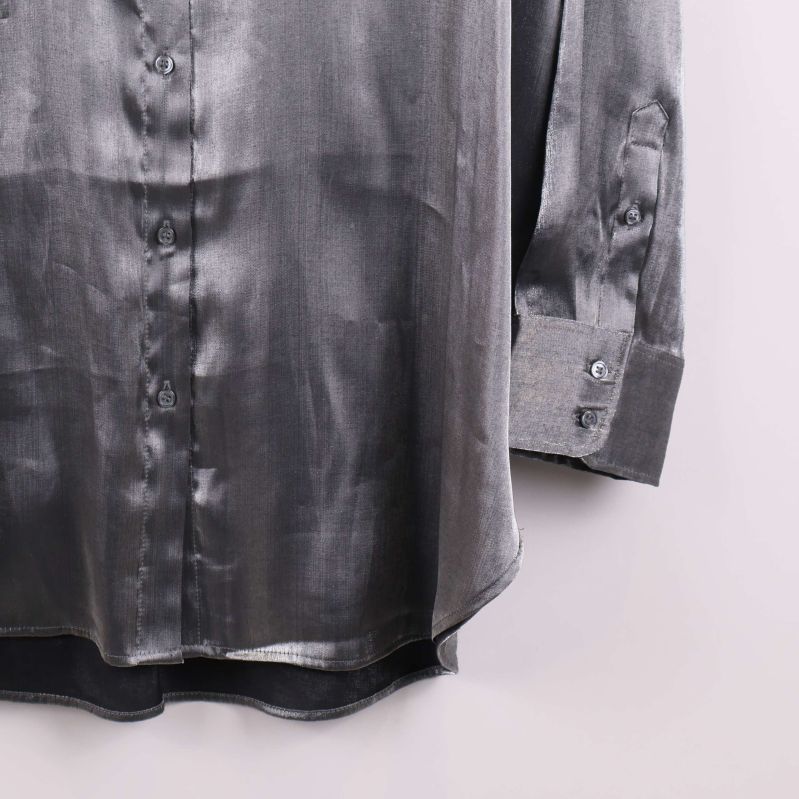 Närbild på skjortans nederkant och manschett i glansigt tyg