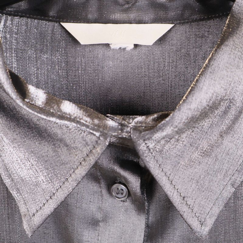 Närbild på skjortkrage och knäppning med glansig struktur