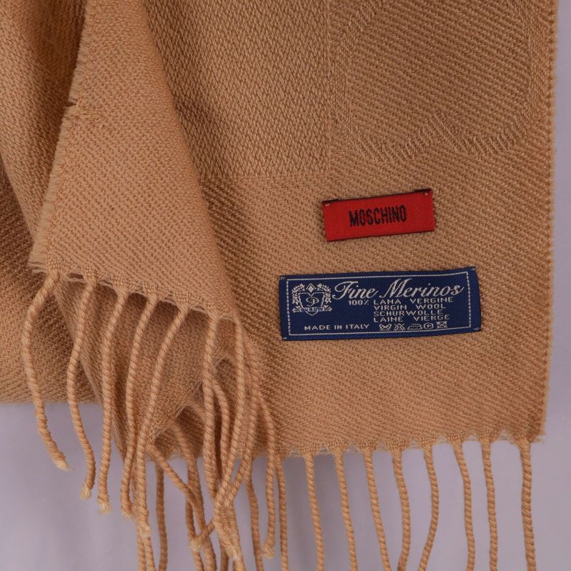 Närbild på Moschino-logga och Fine Merino-etikett på halsduk