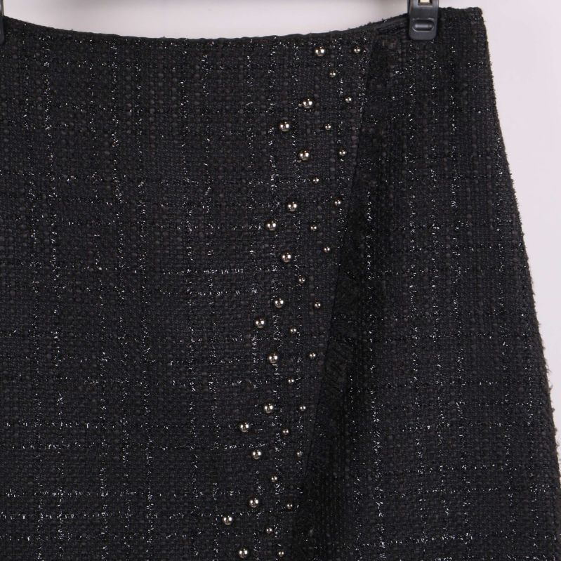 Närbild av kjolens framsida visar nitar och tygstruktur