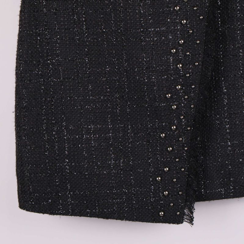 Nederkant av kjol med rå kant och nitar i fokus