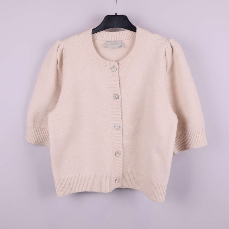 Beige stickad kofta med strassknappar framifrån på galge