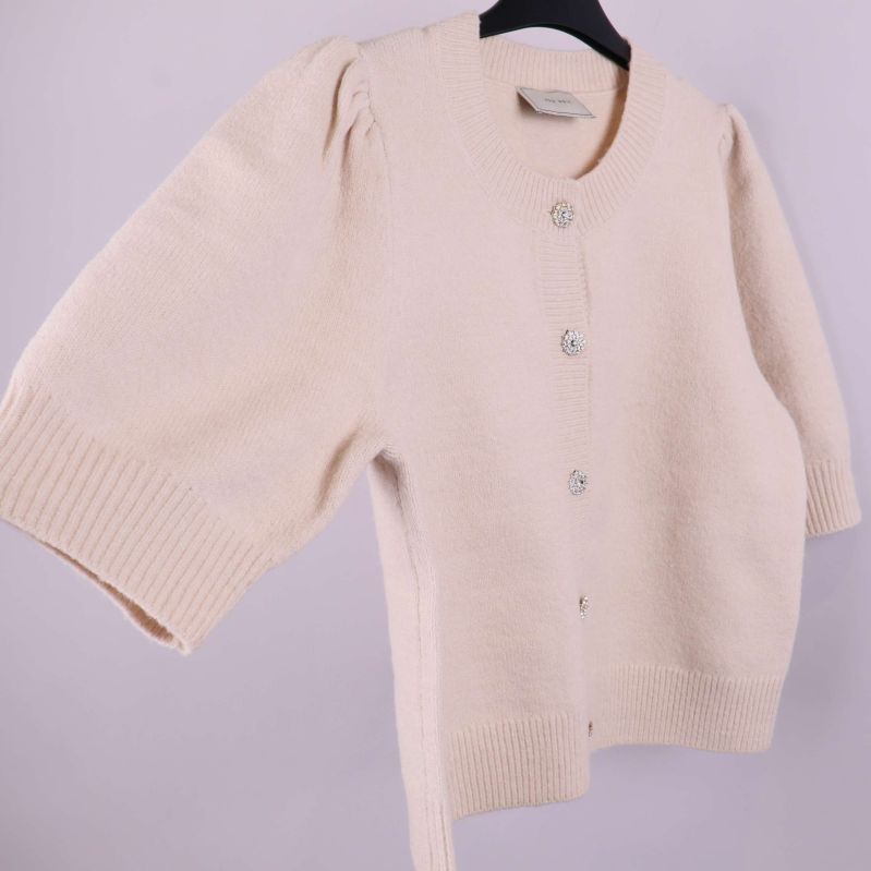 Beige stickad kofta i sned vinkel med strassknappar