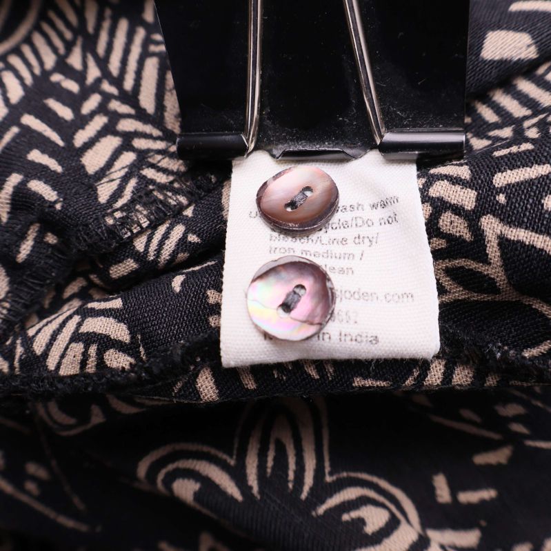 Extra knappar fästa vid tvättrådslabel inuti plagget