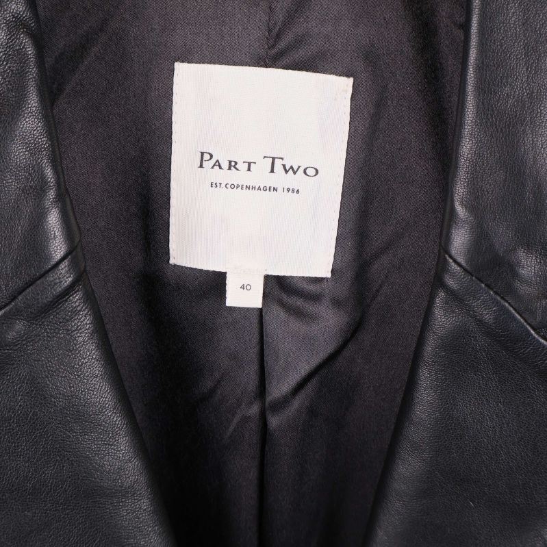 Nära på vit etikett med Part Two-logga i kavajens insida