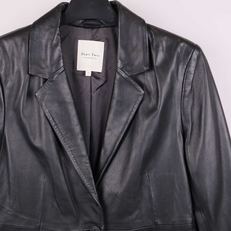 Närbild på krage och axelparti av svart skinnkavaj