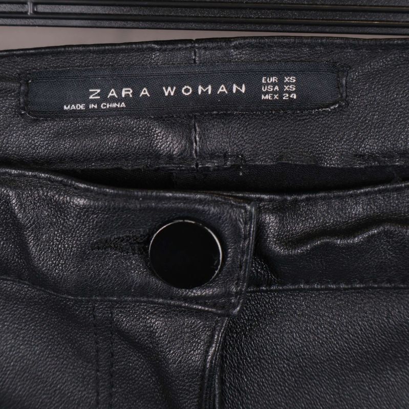 Närbild på midja med ZARA WOMAN etikett och knapp