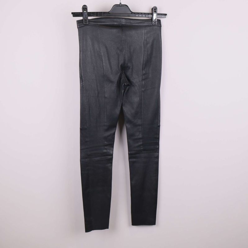 Baksida av svarta byxor i läderlook på galge