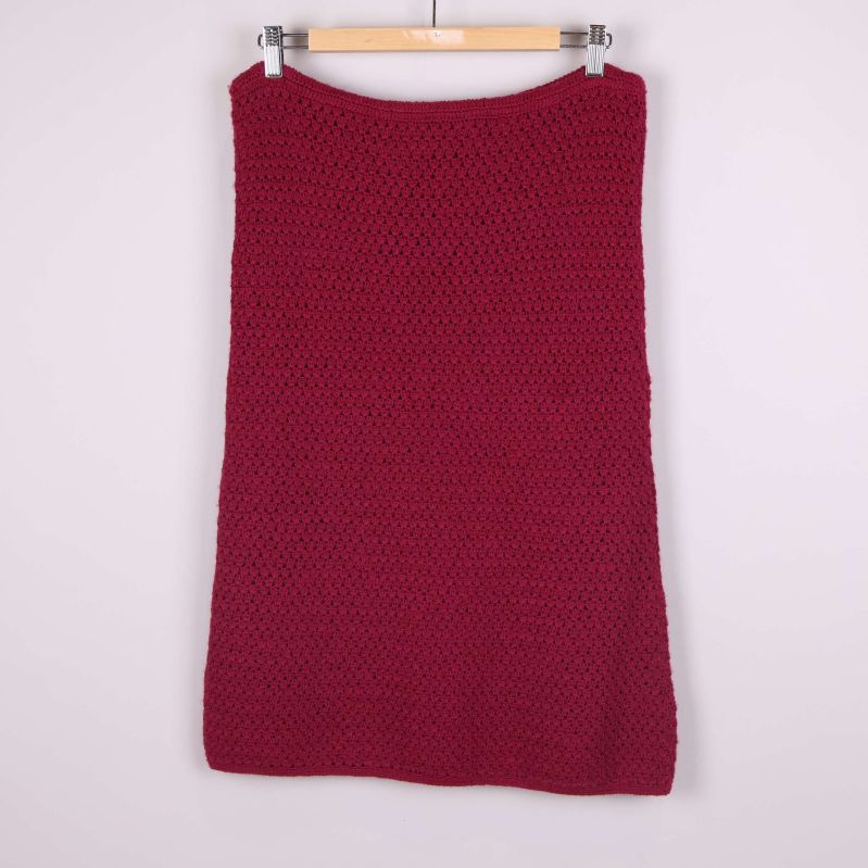 Stickad mörkröd kjol sedd bakifrån mot ljus bakgrund