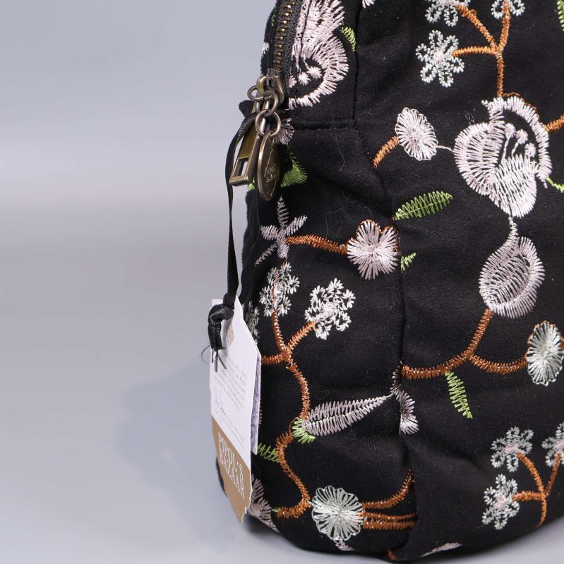 Närbild på dragkedja och broderade detaljer på necessären