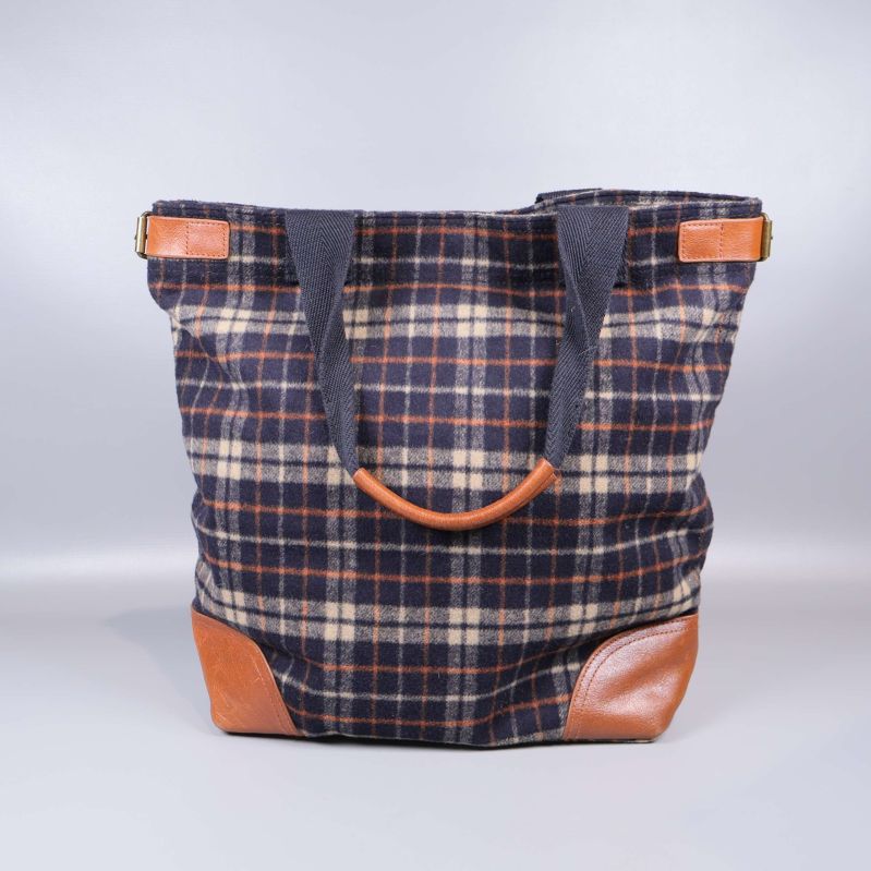 Baksida av rutig tygväska med dubbelhandtag i tyg och läder