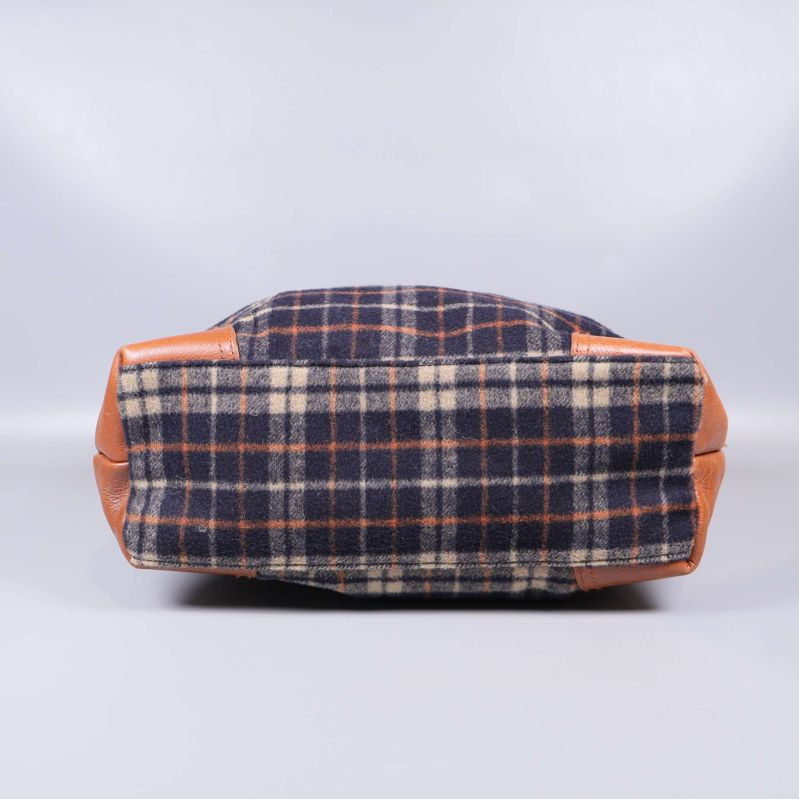 Undersidan av rutig tygväska med hörn i brunt läder