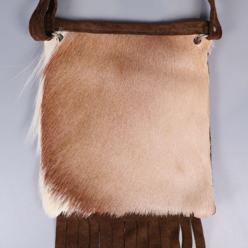 Närbild på väskans ljusa päls och fransar