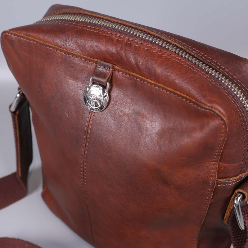 Detaljbild på läderväska med metalldragkedja och knapp