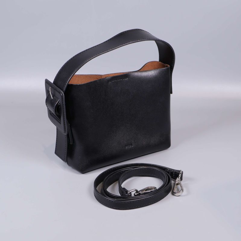 Väska med avtagbar rem liggande framför