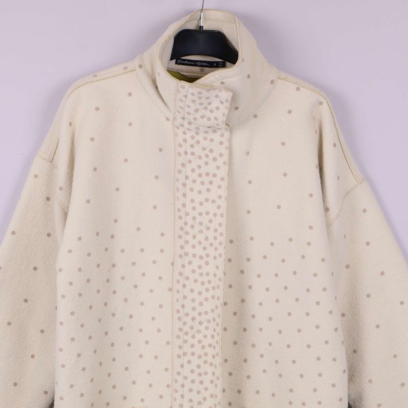 Övre delen av prickig ullkappa med hög krage och knäppning