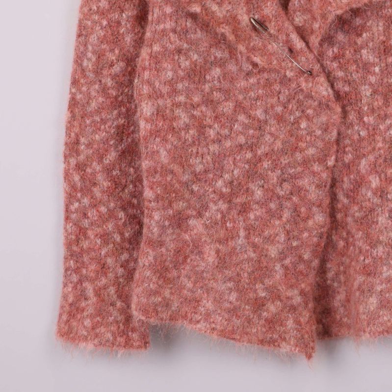 Stickad ärm och nederkant på aprikos jacka i närbild