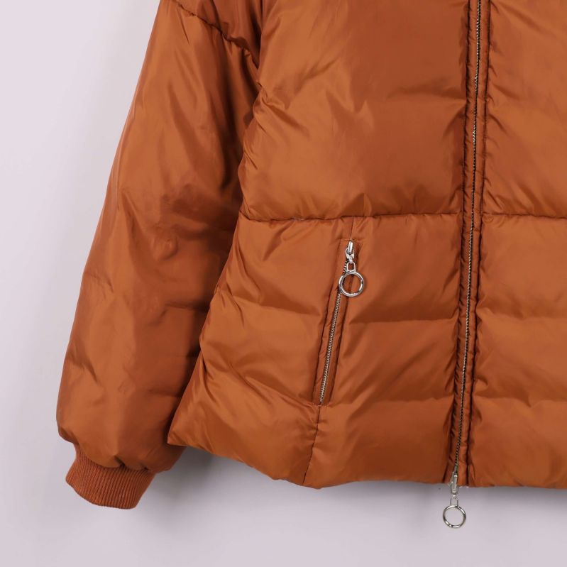 Närbild på fickor och dragkedjor med ringar på brun jacka