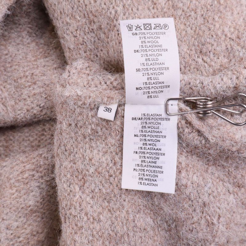 Materiallapp med fiberinnehåll i beige kofta