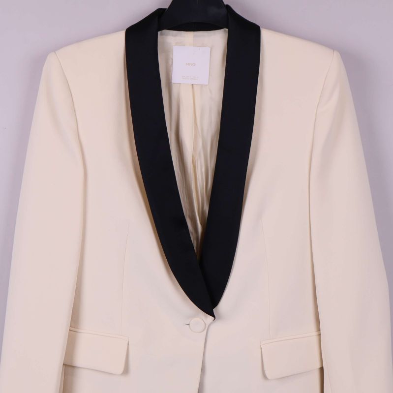 Detalj på cremevit kavaj med svart sjalkrage och fickor