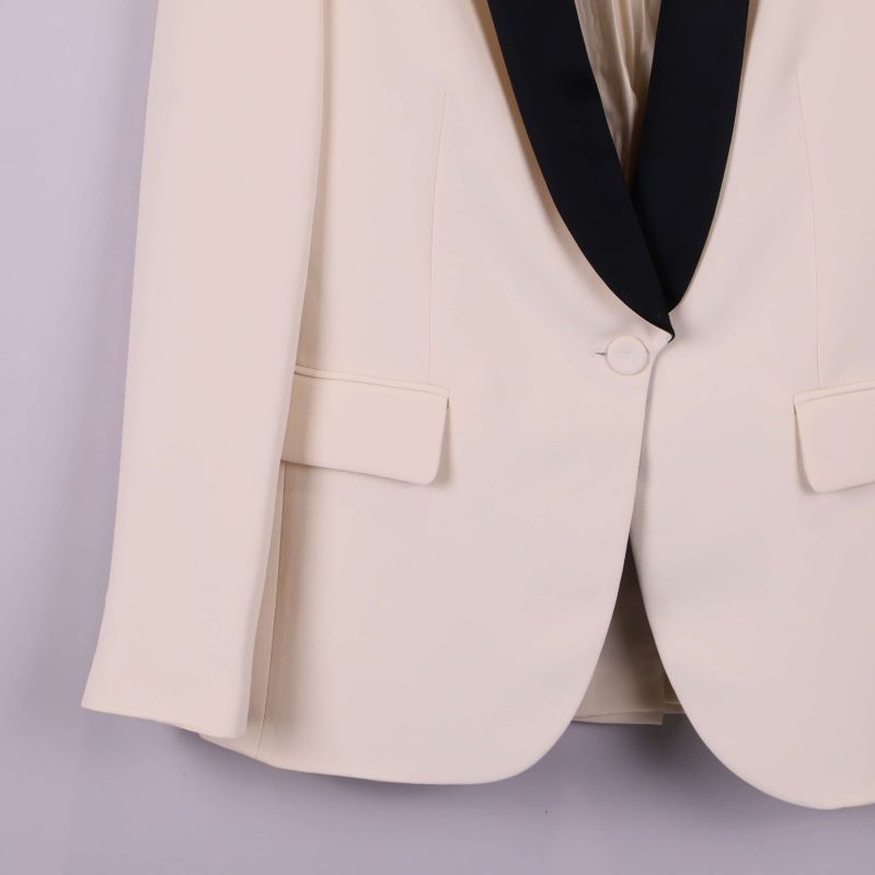 Närbild på kavajknapp och nedre del av ärm