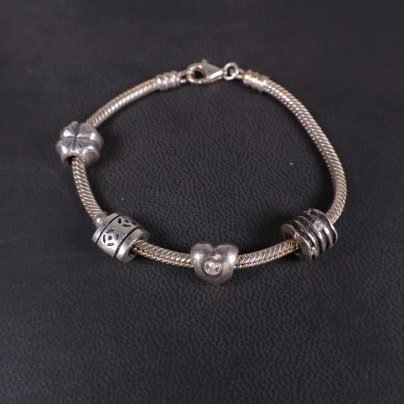 Närbild på armbandslänk med fyra olika berlocker