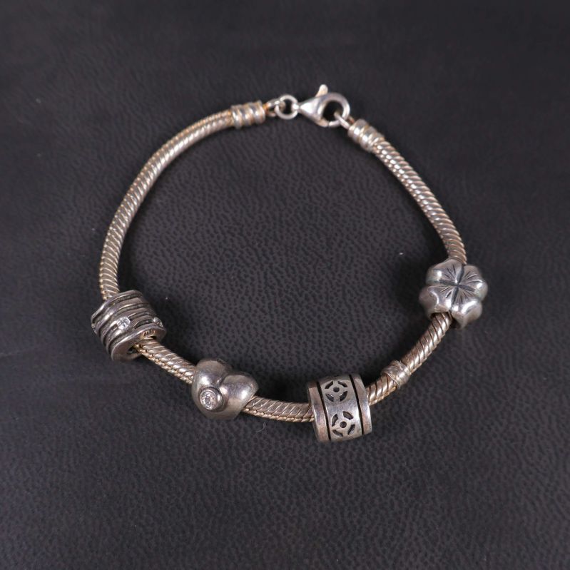 Armbandslänk i silverfärg med stängd lås och berlocker