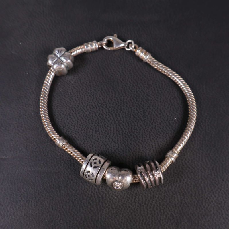 Armbandslänk liggande plant med berlocker synliga