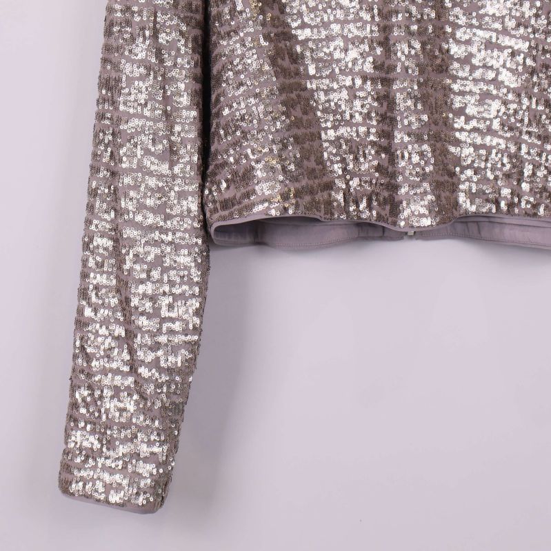 Detaljbild på paljettoppens höger ärm och nederkant