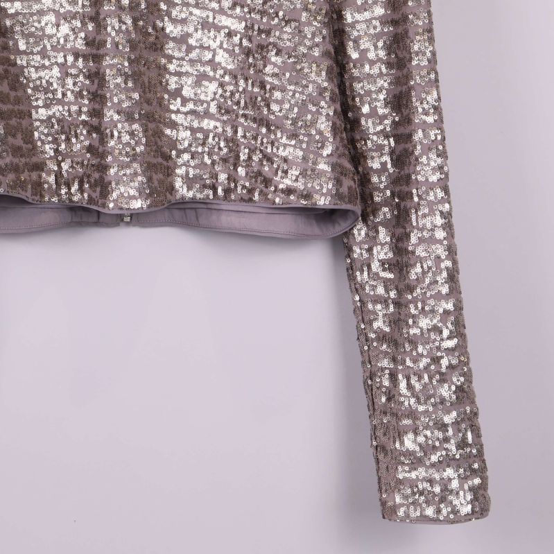 Detaljbild på paljettoppens vänster ärm och nederkant